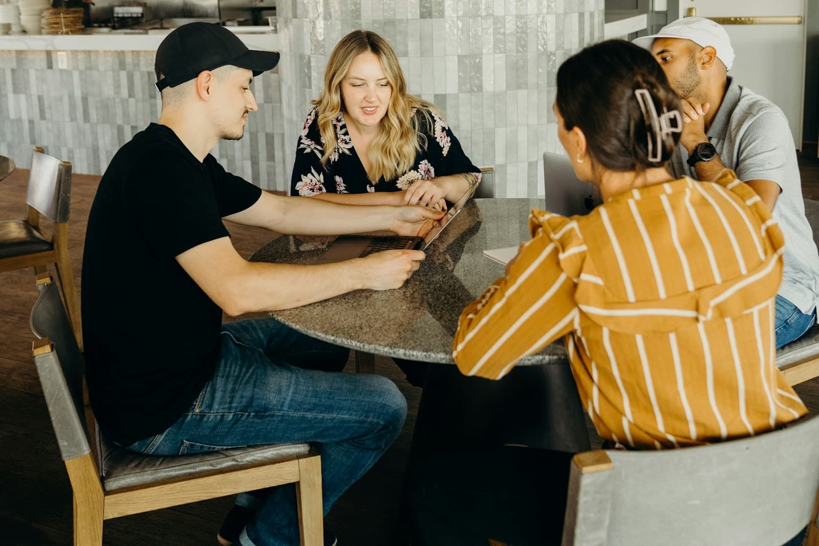Cinq personnes rient ensemble autour d’une table, en pleine conversation.